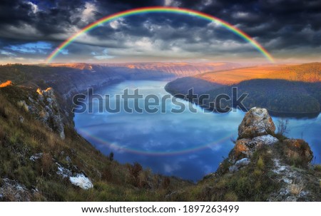 colorful rainbow over river canyon. autumn landscape