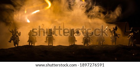 Medieval battle scene. Silhouettes of figures as separate objects, fight between warriors at night. Creative artwork decoration. Foggy background. Selective focus Royalty-Free Stock Photo #1897276591