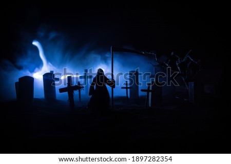 Scary view of grim reaper at cemetery with spooky cloudy sky and fog, Horror Halloween concept. Selective focus