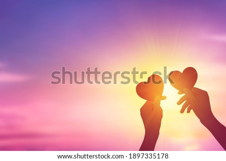 Silhouette hands holding heart from  at sunlight background. Love concept.