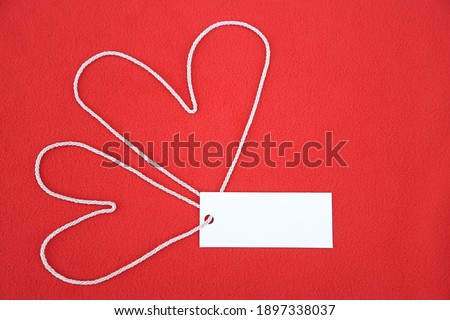 Fabric robe on red fabric background with blank space on tag as a Valentine's day photo for create about love in celebrations 