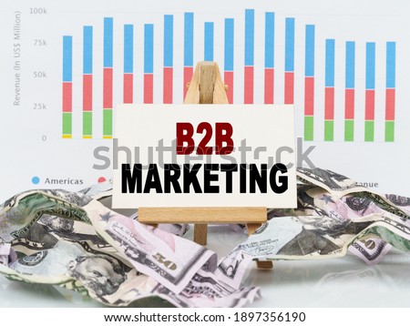 Business and finance concept. Among financial charts and money is a sign with the text - B2B MARKETING