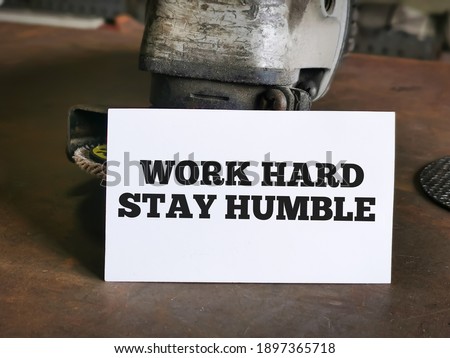 White card written WORK HARD STAY HUMBLE on tools table.Motivational quote.