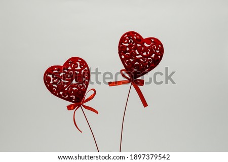 Two red hearts on sticks with a ribbon on a white background, copy space, top view. Minimalistic design for Valentine's Day