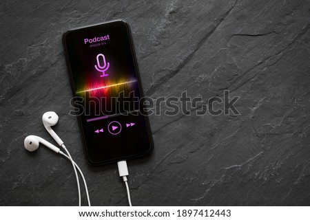 Earphones and mobile phone with podcast app on screen Royalty-Free Stock Photo #1897412443