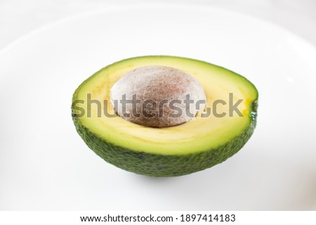 Half fresh avocado fruit on white plate.