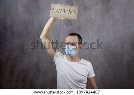 Man holding a stay home poster on a gray background