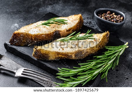 Halibut fish steak with rosemary. Black background. Top view.