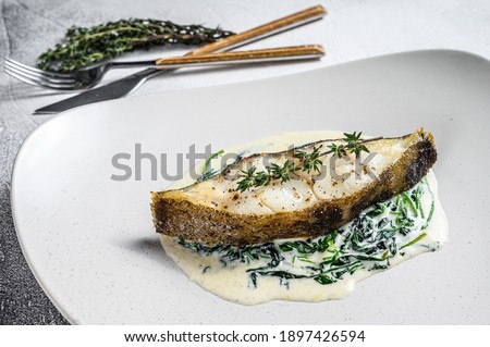 Baked Halibut fish steak with spinach. White background. Top view.