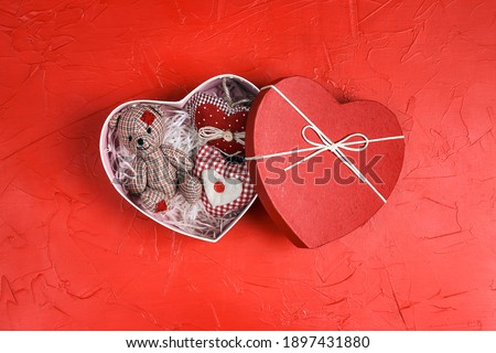 Little cute toy bear with hearts in a gift box on a red background. Valentine's day concept.
