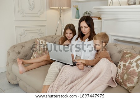 Mom daughter and son play on laptop. Family recreation and leisure
