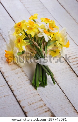 Bunch of different daffodils on white wooden planks. Selective focus, vertical, top view.