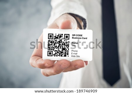 Businessman holding QR code business card with personal data. Modern technology concept.