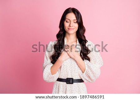Photo portrait of sincere dreamy girl thankful keeping hands on chest isolated on pastel pink color background