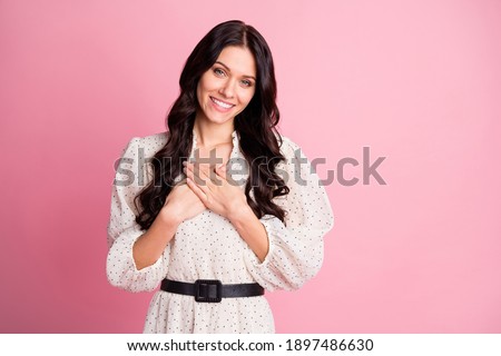 Photo portrait of grateful smiling girl thankful keeping hands on chest isolated on pastel pink color background