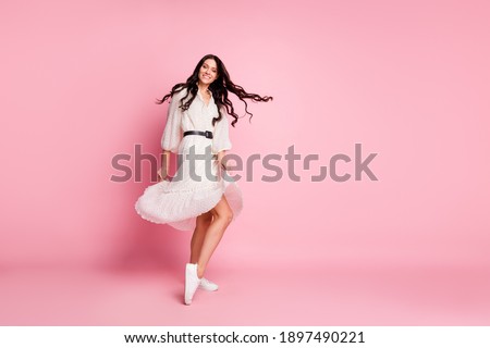 Full length body size photo of female student smiling dancing at party in white dress isolated on pastel pink color background empty space