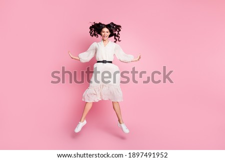Full length body size photo of carefree playful woman in white dress jumping smiling isolated pastel pink color background