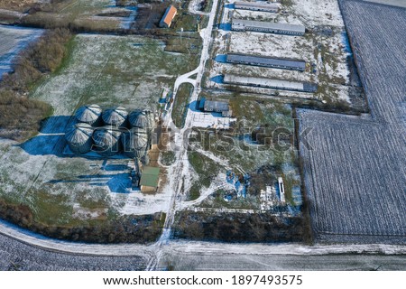 Snowy silos in winter. industrial elevator dryers, building exterior, storage and drying of cereals, wheat, corn, soybeans, sunflowers. Drone aerial view in Europe in Hungary