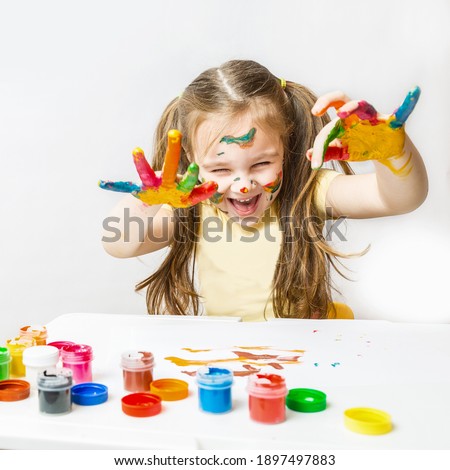 children's creativity. Portrait cheerful, laughing caucasian preschool little girl with face and hands painted at home