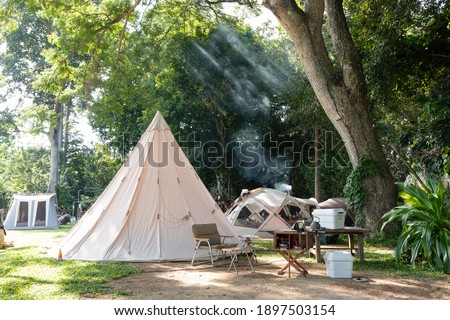 A large white traditional teepee tent with luxurious glamping interiorwith desk and chairs in forest,holidayvacation,Camping Royalty-Free Stock Photo #1897503154