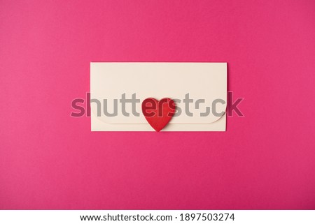 Envelope and red heart on the hot pink background. Flat lay. Romantic love letter for Valentine's day concept.