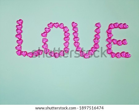 Word love made of small pink hearts on blue background