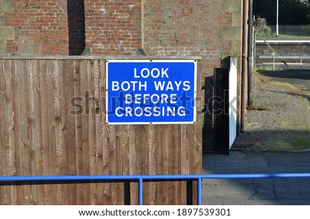 Close Up of Outdoor Blue Metal Crossing Sign on Wooden Fence 