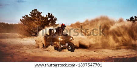 Teen riding ATV in sand dunes making a turn in the sand Royalty-Free Stock Photo #1897547701