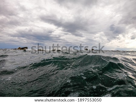 cloudy sky above the sea surface. waves crash into stones sticking out of the water