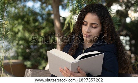 young brazilian girl in the park with a book