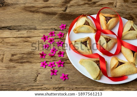Hamantaschen cookies or hamans ears and  spring flowers  for Purim celebration (Jewish carnival holiday).  Selective focus.