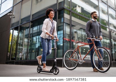 Happy business people going to work with bicycle, electric scooter on urban street Royalty-Free Stock Photo #1897567381