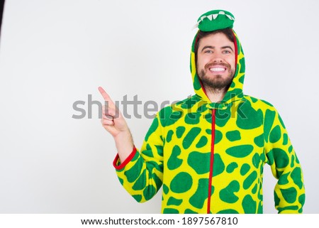 young caucasian man wearing a pajama standing against white background looking at camera indicating finger empty space sales