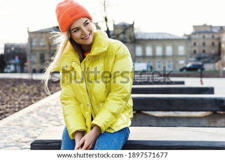 Portrait of  stylish girl wearing yellow puffer and orange knitted hat  Royalty-Free Stock Photo #1897571677