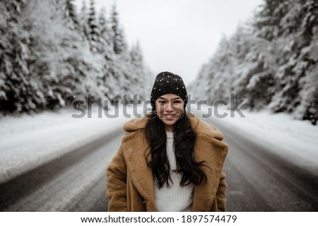 A shallow focus shot of a young smiling Hispanic female posing in the scenic woody terrain