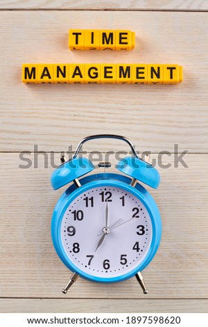 Time organisation for personal efficiency. Clock as a symbol of time on the wooden table.