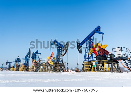 Oil and gas industry. Working oil pump jack on a oil field at winter sunny day. Oil production in Siberia