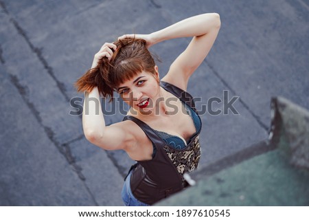 a beautiful girl in a corset stands on the roof of a high house
