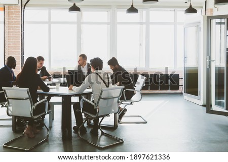 Group of young business people working and communicating while sitting at the office desk together with colleagues sitting. business meeting