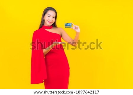 Portrait beautiful young asian woman with credit card on yellow background
