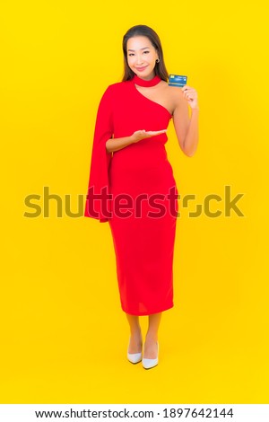 Portrait beautiful young asian woman with credit card on yellow background