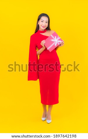 Portrait beautiful young asian woman with red gift box on yellow background