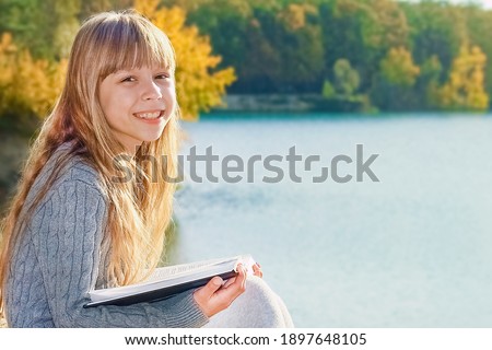 Happy child reading book on nature education in park travel