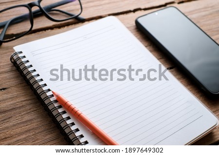 Wooden table with notebook, eyeglasses, pen, decorative plants. Top view of wooden table and stationery with copy space, flat lay.