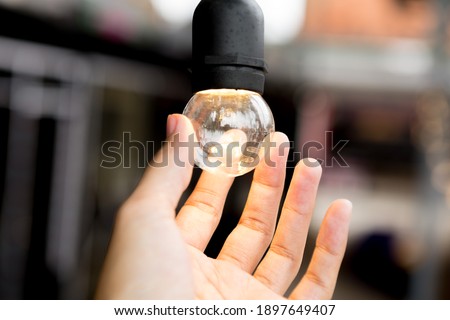 Selective focus of Hand holding a light bulb on blurred background for Clean energy for environment and copy space