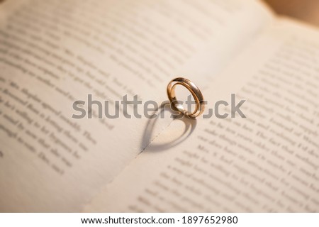 Two wedding Ring on the bible with shadow of heart shape on the open page. Engagement, wedding and nuptials. Marriage. A vow of love. Royalty-Free Stock Photo #1897652980