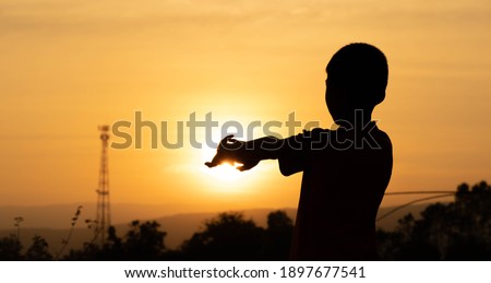 Shadow children exercise on morning of golden sky background, children raise hand for yoga on sunrise, blurred hills and clouds on silhouette wallpaper, lifestyle active of child for relaxing time 