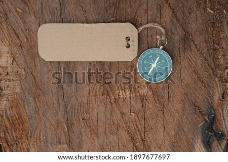 Magnetic compass and empty paper tag at outdoor, space available for word, message. Selective focus