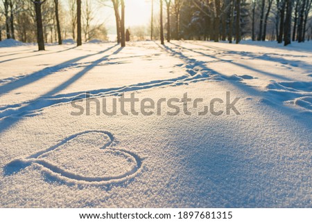 Drawn heart in a snow landscape.Winter evening sunset nice background. Royalty-Free Stock Photo #1897681315