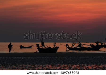 Silhouette of photographer and fishing boat during after the sunset.